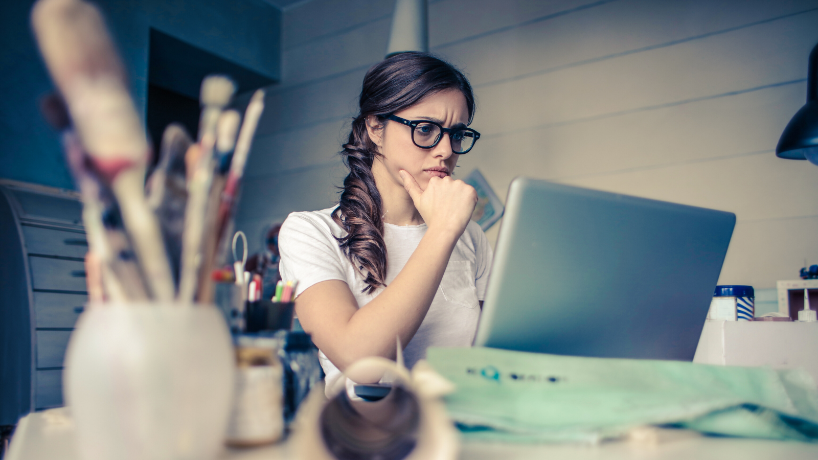 Frau sitzt mit skeptischem Blick vor ihrem Notebook.