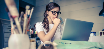 Frau sitzt mit skeptischem Blick vor ihrem Notebook.